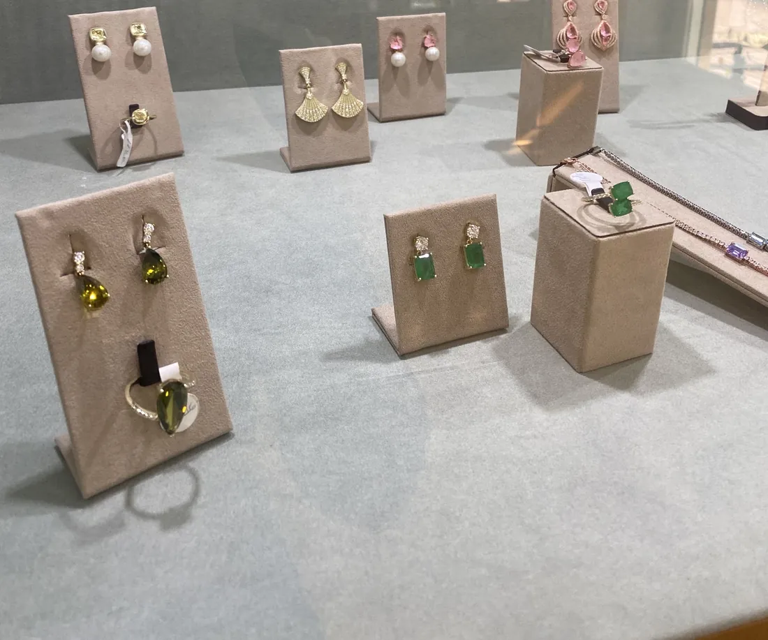Pendientes con piedras de color y perlas sobre expositores de ante